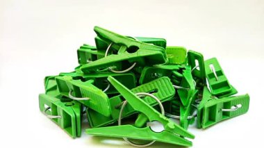 Beyaz arka planda dönen yeşil çamaşır mandalları, ev için plastik mandallar ya da elbise askıları.