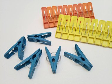 Çamaşır klipsleri, otanj setleri ve sarı plastik broşlar veya beyaz arka plandaki ev için elbise askıları.