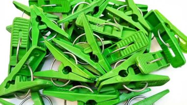 Beyaz arka planda dönen yeşil çamaşır klipsleri, ev için plastik elbise iğneleri ya da elbise askıları