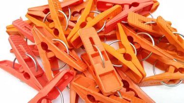 Beyaz arka planda dönen turuncu çamaşır klipsleri, ev için plastik mandallar veya elbise askıları.