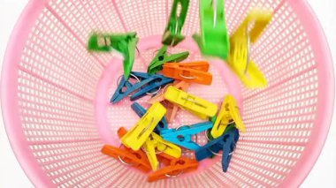Beyaz arka planda çamaşır mandalları, çok renkli plastik çamaşır tokaları ya da mandallarla dolu bir sepet.