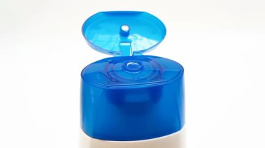Beyaz zemin üzerinde dönen açık plastik bir şişe kapağı, mavi renk açık üst kapak, kozmetik ya da şampuan kapağı beyaza izole edilmiş.