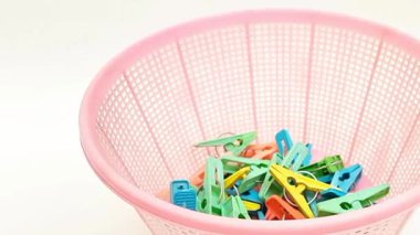 Beyaz hareket halindeki arka plan, çok renkli plastik çamaşır tokaları ya da elbise askılarıyla dolu bir sepet.