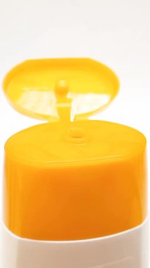 Beyaz zemin üzerinde dönen açık plastik bir şişe kapağı, sarı renk açık üst kapak, kozmetik ya da şampuan kapağı beyaz, dikey klipste izole edilmiş.