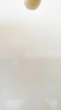 Beyaz krem dokusu, yüz yıkama, şampuan, temizleyici, kozmetik ya da cilt ürünleri beyaz arka planda, dikey klipste düşüyor.,
