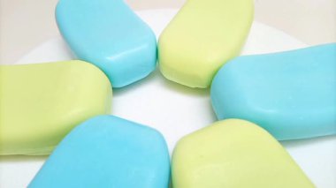 Sabun barı. Beyaz arka planda dönen banyo için mavi ve sarı sabunlar. Vücut ve yüz için aromatik sabun. mavi ve sarı banyo sabunu parçaları