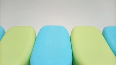Sabun barı. Banyo için mavi ve sarı sabunlar beyaz arka planda ilerliyorlar. Vücut ve yüz için aromatik sabun. mavi ve sarı banyo sabunu parçaları