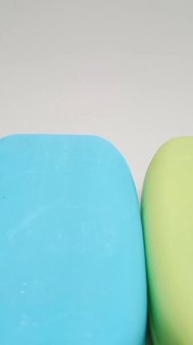 Sabun barı. Banyo için mavi ve sarı sabunlar beyaz arka planda ilerliyorlar. Vücut ve yüz için aromatik sabun. Mavi ve sarı banyo sabunu parçaları, dikey klipsli