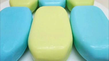Sabun barı. Beyaz arka planda hareket eden banyo için mavi ve sarı sabunlar. Yakın çekim, vücut ve yüz için aromatik sabun. mavi ve sarı banyo sabunu parçaları