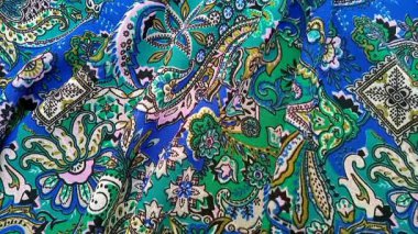 Paisley desenli kumaş katmanı, kıvrımlı, gözyaşı damlası şekilli motifler Pers kökenli, mavi ve yeşil gibi canlı renkler, desen