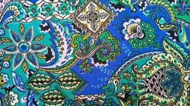 Paisley desenli kumaş detayı dönen arka plan, kıvrımlı, gözyaşı damlası şekilli motifler İran kökenli mavi ve yeşil gibi canlı renklerle, desen