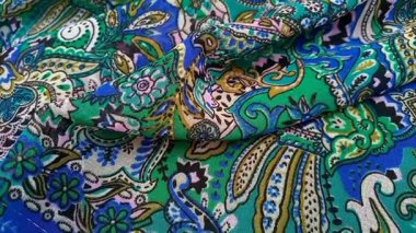 Paisley desenli kumaş detayı kıvrımlı hareket eden arka plan, kıvrımlı, gözyaşı damlası şekilli motifler Pers kökenli canlı renkler, mavi ve yeşil gibi, doku