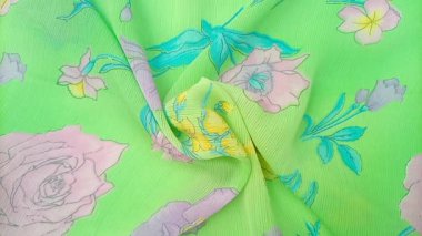 Çiçek desenli dönüşümlü çiçekler, güller, nergisler ve parlak yeşil arkaplana saçılmış pembe, mor ve sarı tonlarında diğer çiçekler de dahil olmak üzere çeşitli çiçekler içerir.,