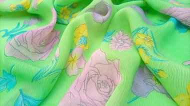 Kırışmış çiçek deseninde güller, nergisler ve pembe, mor ve sarı tonlarında diğer çiçekler parlak yeşil bir arka plana dağılmış.