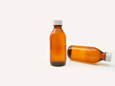 Beyaz arka planda izole edilmiş alüminyum kapaklı kehribar cam şişeler ilaç, şurup, gerekli yağlar ve kozmetik ürünleri için iki kahverengi cam şişe.