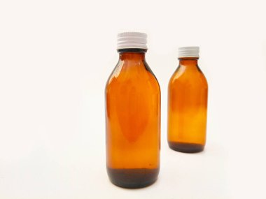 Beyaz arka planda izole edilmiş alüminyum kapaklı kehribar cam şişeler ilaç, şurup, gerekli yağlar ve kozmetik ürünleri için iki kahverengi cam şişe.