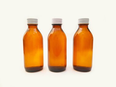 Beyaz zemin üzerinde alüminyum kapaklı kehribar cam şişeler eczacılık, şurup, gerekli yağlar ve kozmetik ürünleri için 3 kahverengi cam şişe.