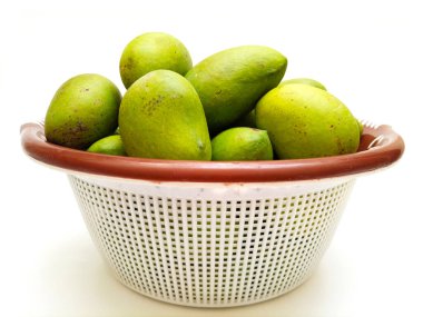 Beyaz arka planda izole edilmiş sepetteki taze yeşil mango meyvesi, tropikal meyve, olgunlaşmamış mango turşusu.