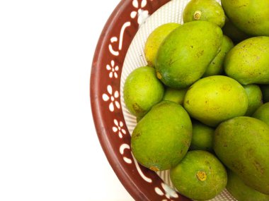 Fotokopi alanı, tropikal meyve ve turşu için olgunlaşmamış mango içeren beyaz arka planda bulunan sepetteki taze yeşil mango meyvesi.