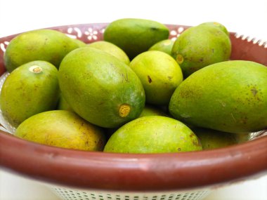 Beyaz arka planda izole edilmiş sepetteki taze yeşil mango meyvesi, yakın plan, tropik meyve, olgunlaşmamış mango turşusu