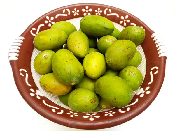Beyaz arka planda izole edilmiş sepetteki taze yeşil mango meyvesi, tropikal meyve, olgunlaşmamış mango turşusu.
