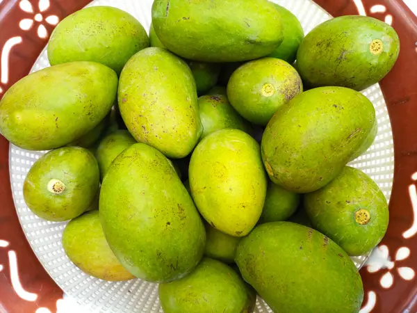 Beyaz arka planda izole edilmiş sepetteki taze yeşil mango meyvesi, yakın plan, tropik meyve, olgunlaşmamış mango turşusu