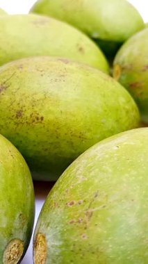 Beyaz arka planda taze yeşil mango meyveleri hareket ediyor, tropikal meyveler, turşu için olgunlaşmamış mangolar, dikey klipler.
