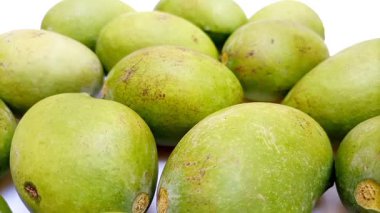 Beyaz arka planda taze yeşil mango meyveleri hareket ediyor, tropikal meyve, olgunlaşmamış mango turşusu