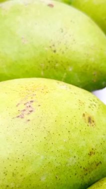 Beyaz arka planda taze yeşil mango meyveleri hareket ediyor, tropikal meyveler, turşu için olgunlaşmamış mangolar, dikey klipler.