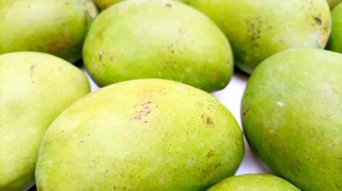 Beyaz arka planda taze yeşil mango meyveleri hareket ediyor, tropikal meyve, olgunlaşmamış mango turşusu