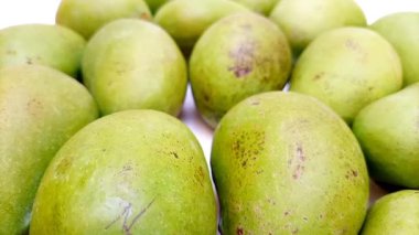 Beyaz arka planda taze yeşil mango meyveleri döner, tropikal meyve, olgunlaşmamış mango turşusu