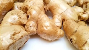 Beyaz zemin üzerinde taze zencefil kökleri veya zencefil rhizomu hareket ediyor, yakın plan