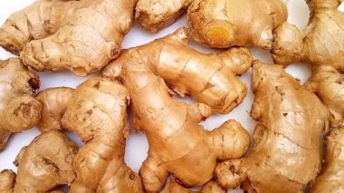 Beyaz arkaplanda dönen taze zencefil kökleri veya zencefil rhizomu, üst görünüm