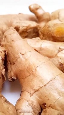 Beyaz arkaplanda dönen taze zencefil kökleri veya zencefil rhizomu, dikey klips