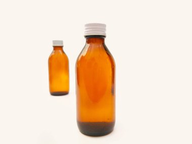 Beyaz arka planda izole edilmiş alüminyum kapaklı kehribar cam şişeler ilaç, şurup, gerekli yağlar ve kozmetik ürünleri için iki kahverengi cam şişe...