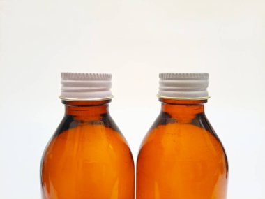 Beyaz arka planda alüminyum kapaklı kehribar cam şişeler, yakın plan, eczacılık, şurup, gerekli yağlar ve kozmetik için kahverengi cam şişe