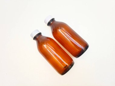 Beyaz arka planda alüminyum kapaklı kehribar cam şişeler ilaç, şurup, gerekli yağlar ve kozmetik ürünleri için iki kahverengi cam şişe.,