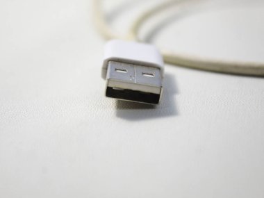 Beyaz ahşap arka plandaki beyaz kırılmış akıllı telefon usb kablosunu kapat.