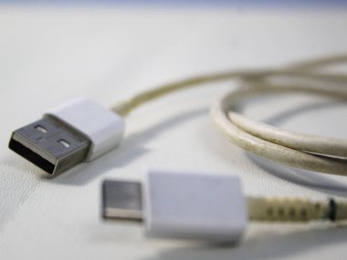 Beyaz ahşap arka plandaki beyaz kırılmış akıllı telefon usb kablosunu kapat.