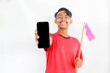 Saçbandı takan ve telefonunu gösteren gülümseyen Asyalı bir adamın portresi. Endonezya 'nın bağımsızlık gününü beyaz arka planla yalıtılmış bir şekilde kutluyor. Endonezya 'nın bağımsızlık günü konsepti
