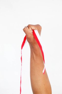 Elinde kırmızı ve beyaz bir kurdele tutan bir adam. Beyaz bir arka planda izole edilmiş, Endonezya Bağımsızlık Günü konseptini temsil ediyor. Endonezya 'nın Bağımsızlık Günü' nü kutlamak