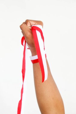 Elinde kırmızı ve beyaz bir kurdele tutan bir adam. Beyaz bir arka planda izole edilmiş, Endonezya Bağımsızlık Günü konseptini temsil ediyor. Endonezya 'nın Bağımsızlık Günü' nü kutlamak