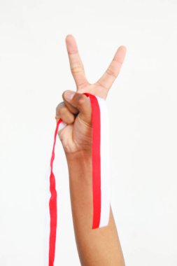 Elinde kırmızı ve beyaz bir kurdele tutan bir adam. Beyaz bir arka planda izole edilmiş, Endonezya Bağımsızlık Günü konseptini temsil ediyor. Endonezya 'nın Bağımsızlık Günü' nü kutlamak