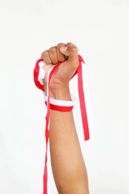 Elinde kırmızı ve beyaz bir kurdele tutan bir adam. Beyaz bir arka planda izole edilmiş, Endonezya Bağımsızlık Günü konseptini temsil ediyor. Endonezya 'nın Bağımsızlık Günü' nü kutlamak