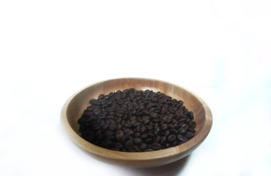 Kahverengi ahşap tabakta kavrulmuş kahve çekirdekleri beyaz arka planda izole edilmiş ve fotokopi alanı var.