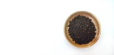 Kahverengi ahşap tabakta kavrulmuş kahve çekirdekleri beyaz arka planda izole edilmiş ve fotokopi alanı var.