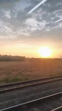 Hareket eden bir trenin içinden gün batımı görüntüsü, makaralar veya kısa video içeriği oluşturmak için mükemmeldir