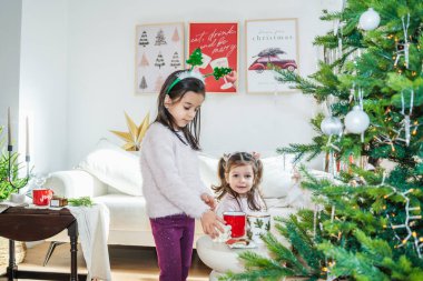 The family enjoys quality time near the decorated Christmas tree. The children unwrap presents, play, and cherish the festive atmosphere of Christmas and New Year. clipart