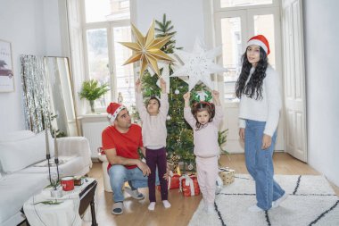 Aile dekore edilmiş Noel ağacının yanında kaliteli zaman geçiriyor. Çocuklar hediyeleri açıyor, oynuyor ve Noel ve Yeni Yıl 'ın şenlikli atmosferini kutluyor..
