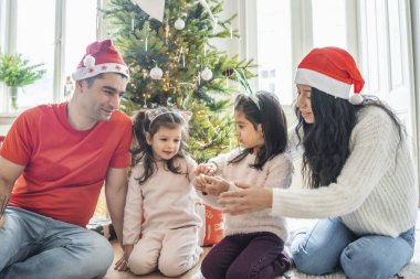 Children lighting sparklers near a festive Christmas tree. Happy moments of anticipation for Christmas and New Year, family warmth, and the magical holiday atmosphere. clipart